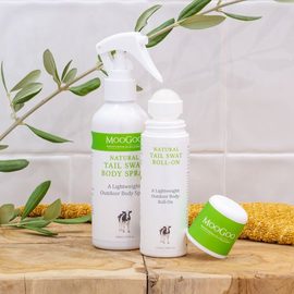 MooGoo Skincare Tail Swat Body Spray and Roll On Bottles on wooden bench.